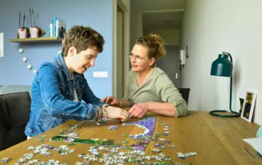 Vrouw met beperking maakt puzzel met andere vrouw