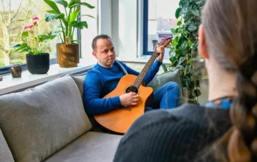 Client speelt op gitaar bij vaktherapie