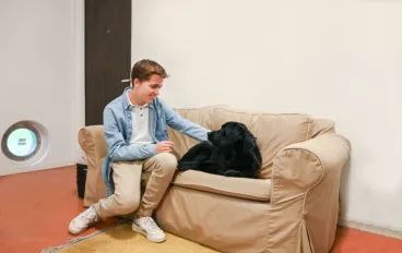 Jongen zit samen met een hond op de bank.