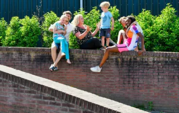 jeugd en ouders zittend op muurtje